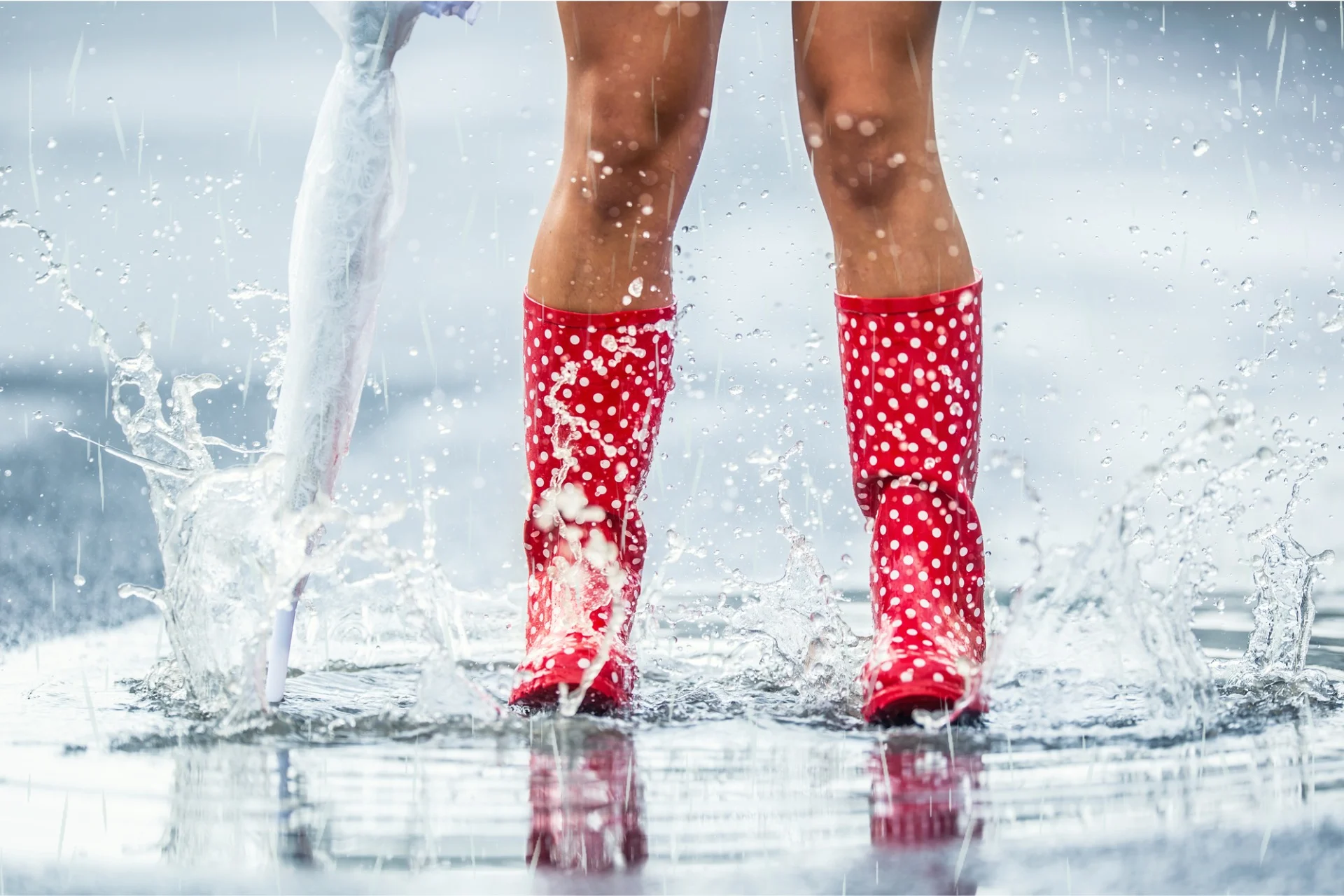 woman's legs in rubber boots jumping in puddle kdulting trend